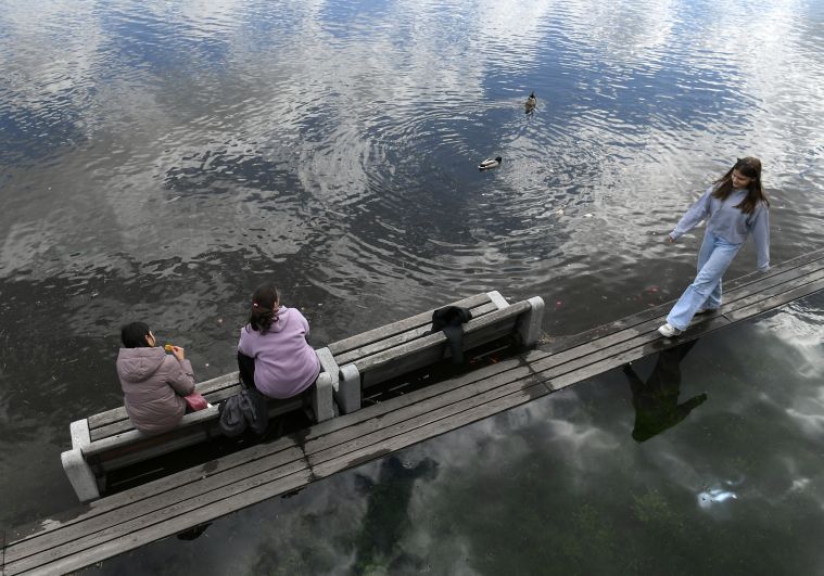 Женщины на затопленной скамейке на набережной Енисея в центре Красноярска
