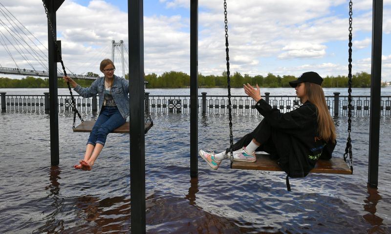 Девушки качаются на качелях на затопленной набережной Енисея в центре Красноярска