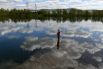 Рыбак на затопленном деревянном тротуаре набережной Енисея в центре Красноярска
