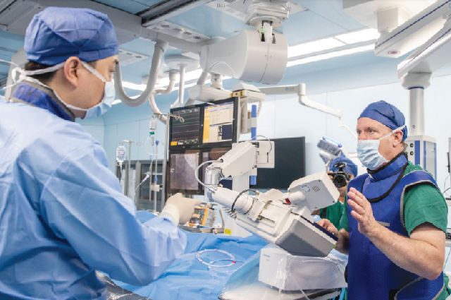 Директор по обучению немецкой компании в сфере медицинских технологий Siemens Healthineers знакомит медицинский персонал больницы Boao Super Hospital, провинция Хайнань, с хирургическим роботом, 13 марта.
