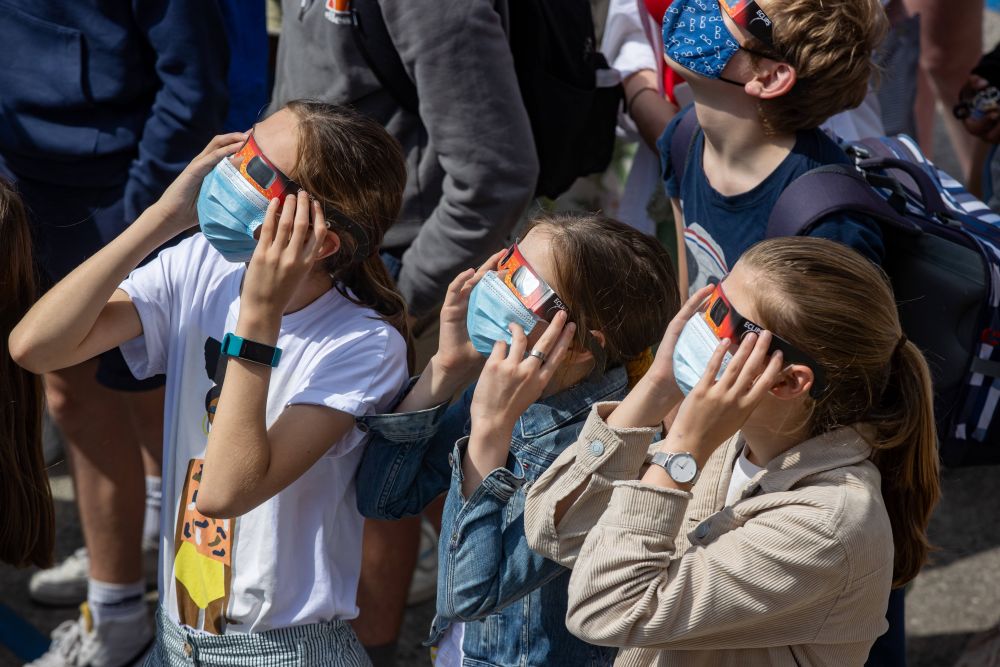 Люди наблюдают солнечное затмение в городе Руселаре (Бельгия)