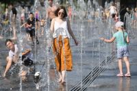 Женщина с собачкой в жаркую погоду гуляет в Парке Горького в Москве.