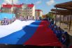 В Салехарде пронесли 15-метровое полотно российского триколора от качельного парка у первой школы до городского сада.