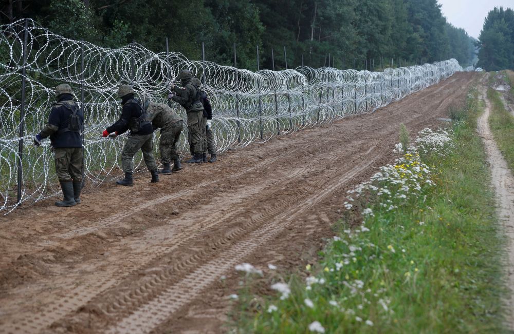 Польские военные устанавливают забор из колючей проволоки на белорусско-польской границе
