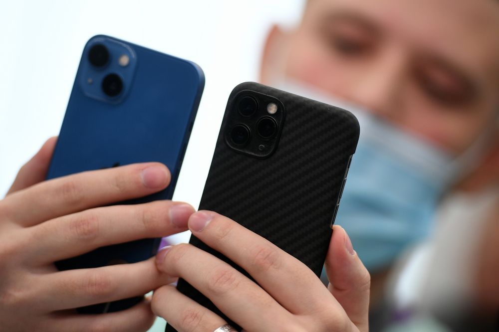Покупатель держит в руках телефоны компании Apple в магазине re:Store