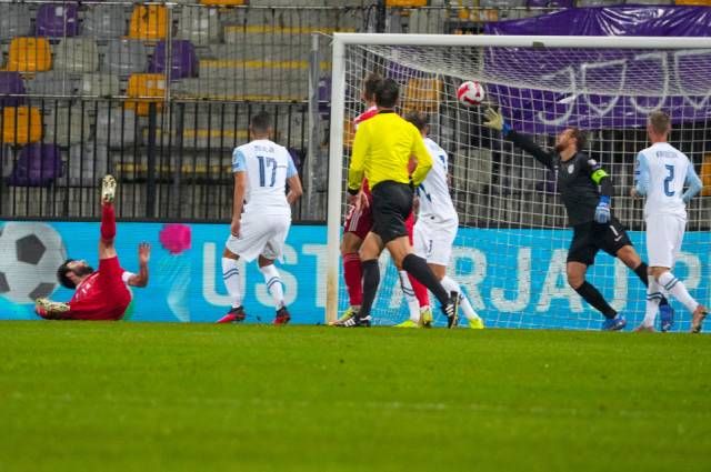 Вратарь сборной Словении по футболу Ян Облак пропускает мяч в свои ворота.