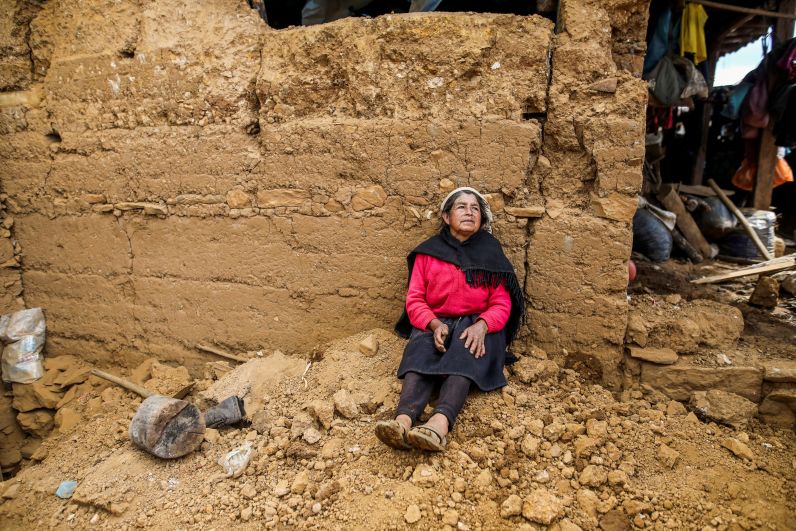 Женщина сидит возле дома, пострадавшего от землетрясения в Халька-Гранде