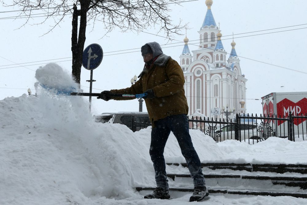 Мужчина убирает снег на одной из улиц в Хабаровске во время снегопада