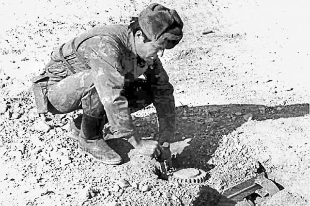 Начальник инженерного отделения Пянджского пограничного отряда майор Олег Улеватый снимает фугас на входе в Мармольское ущелье, 1984 г.