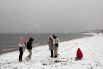 Люди во время снегопада на пляже в пригороде Афин
