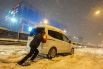  Житель города толкает автомобиль на одной из улиц Стамбула во время снегопада