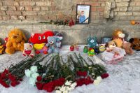 Жители города приносят к дому погибшего мальчика цветы и игрушки.