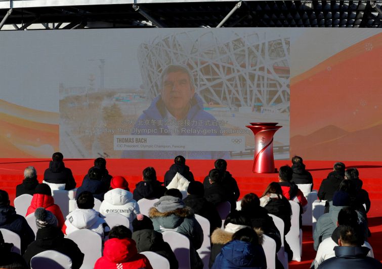 Президент Международного олимпийского комитета (МОК) Томас Бах (на экране) во время церемонии старта эстафеты огня зимней Олимпиады 2022 года в Олимпийском парке.