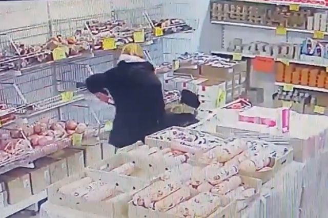 Камера запечатлела, как палка колбасы перекочевала женщине в карман.