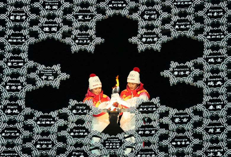 Спортсмены из сборной КНР Динигер Иламуцзян и Цзявен Чжао держат факел с олимпийским огнем на церемонии открытия XXIV зимних Олимпийских игр в Пекине