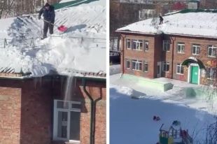 На кадрах видно, как мужчина стоит на крыше двухэтажного здания и счищает с него снег.