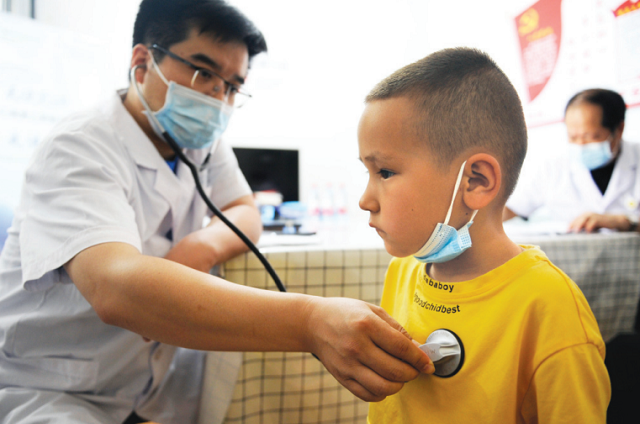 Врач проводит медицинский осмотр ребенка в городе Чанцзи Синьцзян-Уйгурского автономного района в июне прошлого года