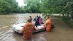 Сотрудники МЧС РФ перевозят местных жителей на надувной лодке через улицу, затопленную после сильных дождей, в Симферопольском районе