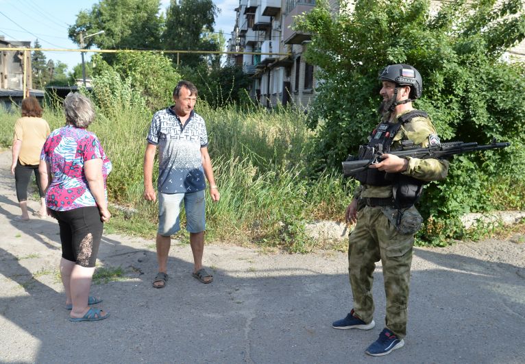 Боец специального полка полиции имени Героя России Ахмата-Хаджи Кадырова разговаривает с жителями Лисичанска