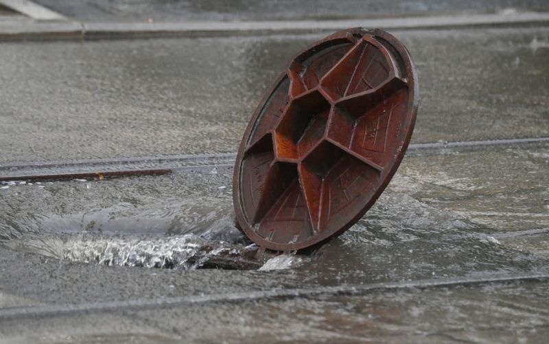 Открытый люк сточной канализации во время дождя в Москве