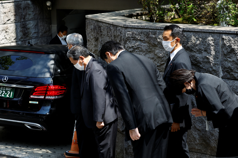 Японские чиновники кланяются после проезда автомобиля с телом Синдзо Абэ. 