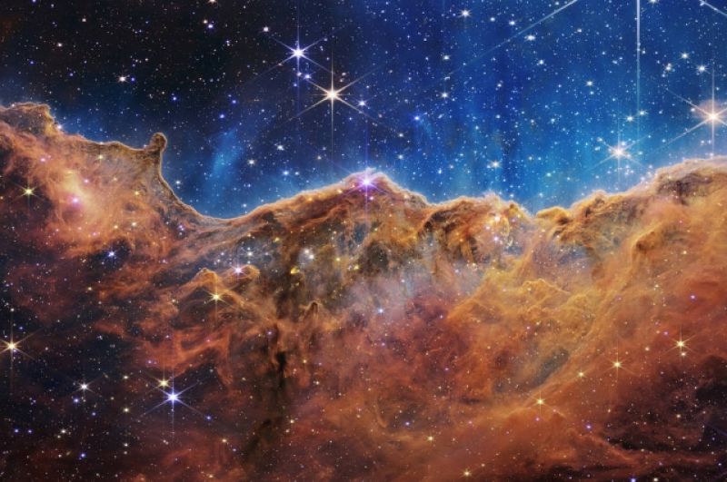 Этот пейзаж из «гор» и «долин», усыпанных сверкающими звездами, на самом деле является краем соседней молодой области звездообразования под названием NGC 3324 в туманности Киля.