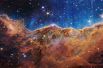 «Космические скалы» туманности Киля видны на изображении, разделенном по горизонтали волнистой линией между облачным ландшафтом, образующим туманность вдоль нижней части, и сравнительно четкой верхней частью, с данными космического телескопа Джеймса Уэбба НАСА.