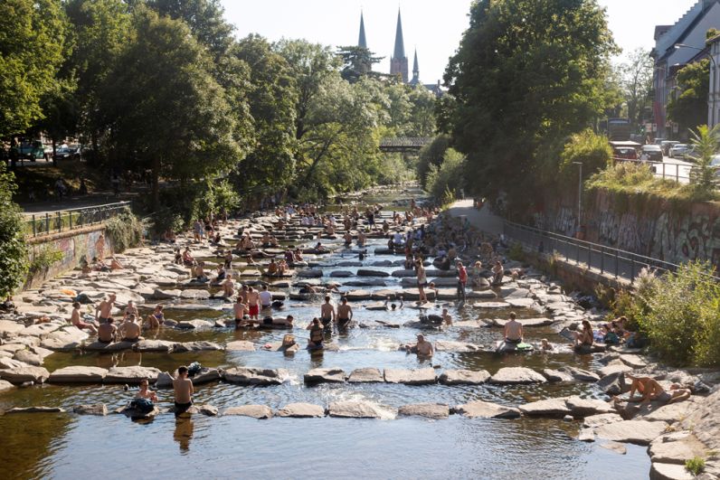 Люди охлаждаются в реке Драйзам во Фрайбурге-им-Брайсгау, Германия.