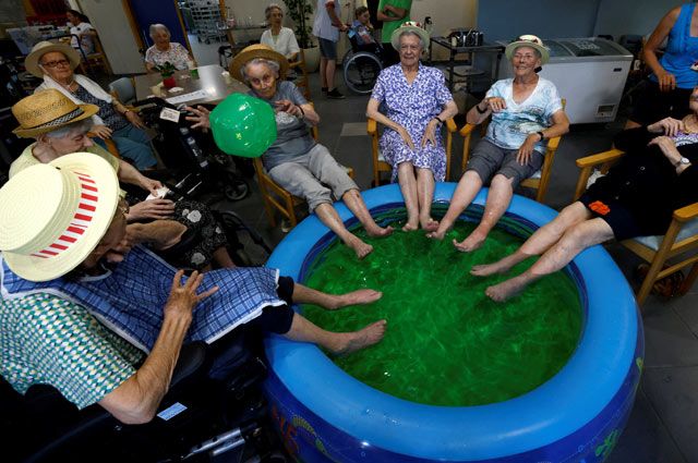 Жители дома престарелых Ter Biest освежают ноги в бассейне. Гримберген, Бельгия.