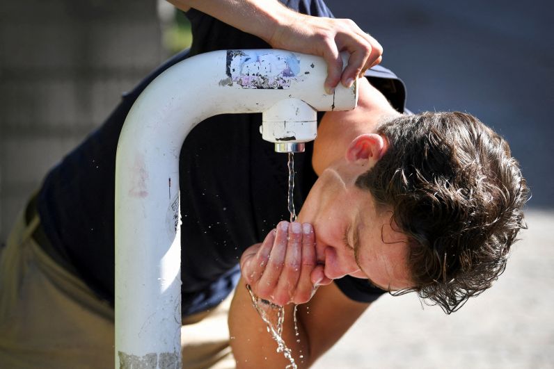 Мужчина пьёт воду в жаркий день из питьевого фонтанчика в Неймегене (Нидерланды)