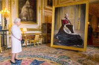 Королева Елизавета II рассматривает свой портрет работы британского художника Генри Уорда, посвященный шестидесятилетию покровительства Британскому Красному Кресту.