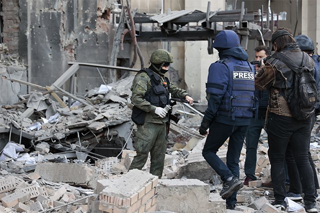 Следователь СЦ РФ и журналисты на месте пострадавшего в результате обстрела со стороны ВСУ здания городской администрации в центре Донецка.