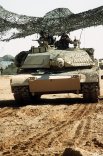 Армейские военнослужащие управляют основным боевым танком M-1A1 Abrams, замаскированным сеткой, во время операции «Буря в пустыне».