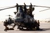 Морские пехотинцы отдыхают рядом с вертолетом CH-46 Sea Knight, пока их товарищи проверяют винты перед взлетом во время операции «Буря в пустыне».