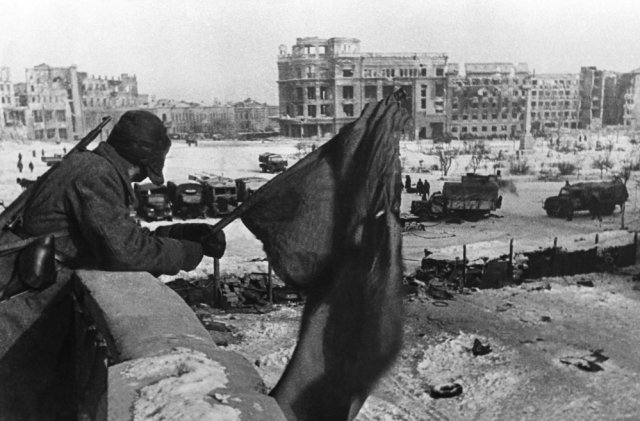 Сталинградская битва. Июль 1942 - февраль 1943 гг. Центральная площадь Сталинграда. Русский солдат держит флаг над освобожденным городом. 31.01.1943