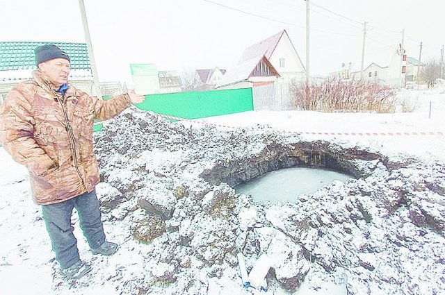Виктор Небога показывает: на месте, где недавно ремонтировали трубу, образовался кратер с водой.
