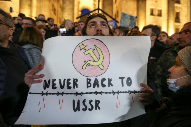 Протестующий  держит плакат с надписью "Никогда обратно в СССР" во время митинга у здания парламента в Тбилиси, Грузия, 8 марта 2023 г.
