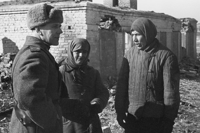 Вернувшиеся в родной город беженцы у своего разрушенного дома беседуют с офицером Красной армии. Город Вязьма. 1943 г.