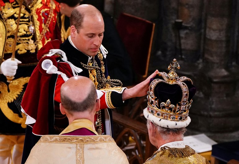 Принц Уэльский прикасается к короне Святого Эдуарда на голове короля Карла III во время церемонии его коронации в Вестминстерском аббатстве.
