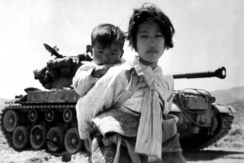 Со своим братом на спине корейская девушка стоит у подбитого танка М-46 в Хэнджу, Корея.