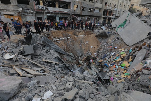 Палестинские арабы около разрушенной пекарни после авиаудара армии Израиля, в результате которого погибли 8 человек, Эль-Магази, Сектор Газа, 25 октября 2023 г.
