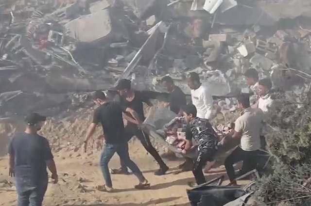 Люди выносят из-под завалов человека, пострадавшего в результате израильских ударов по жилым районам в Газе.