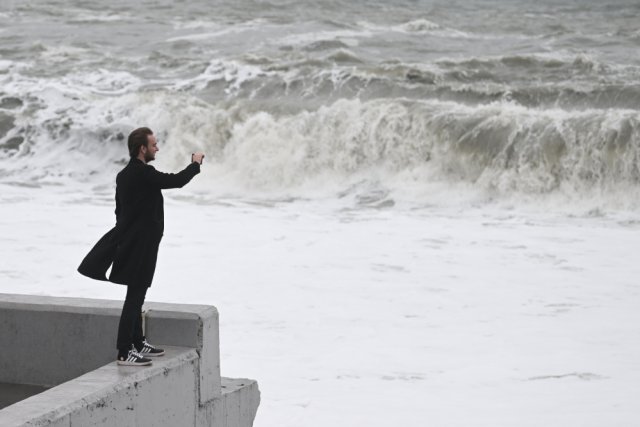 Мужчина фотографирует волны на набережной в Сочи во время шторма.