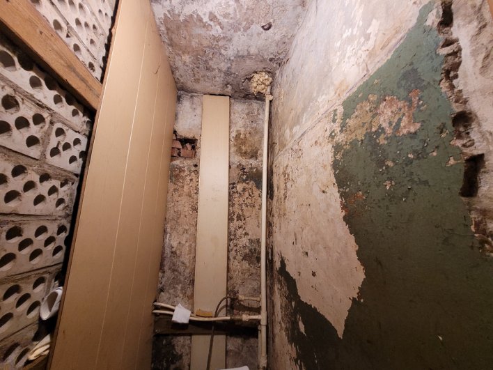 Так выглядят стены туалета. Жильцы начали сами делать ремонт, но поняли, что бессмысленно, когда справа начала отходить стена.