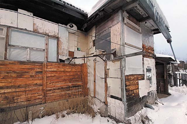 Сергей обивает дом снаружи чем придётся, чтобы хоть как-то утеплить стены.
