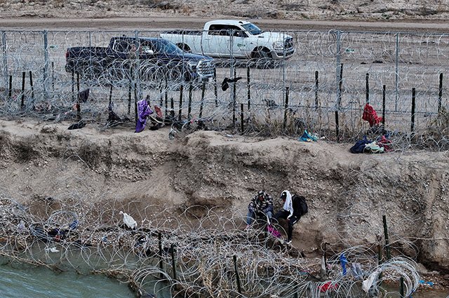 Мигранты у забора из колючей проволоки в Игл-Пасс, штат Техас, США.