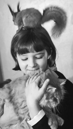 Юннатка Лена Лобанова в кружке юных биологов Московского зоопарка держит кошку, которая выкормила белку. 26 февраля 1968 года.