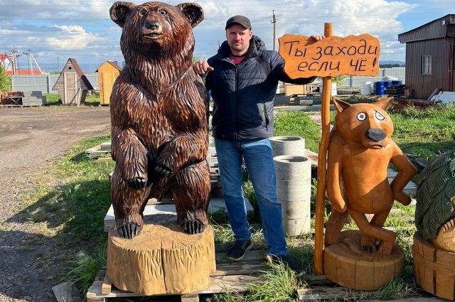 Вячеслав Романов вместе со скульптурами из дерева, которые сделал сам.