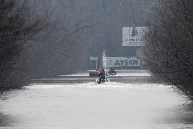 Мужчины плывут на затопленной улице Уральской в Оренбурге. 