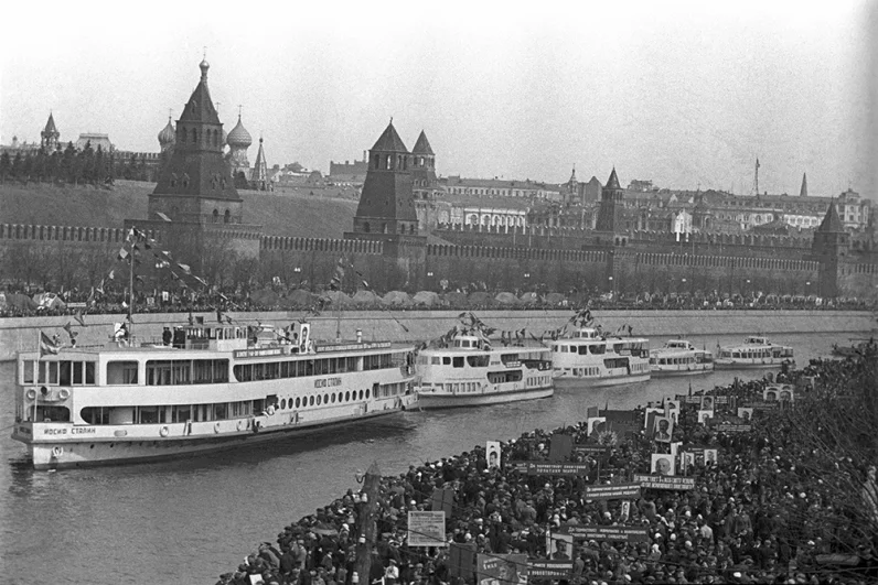 Празднование 1 мая 1938 года в Москве. Корабли Волжской флотилии во главе с пассажирским пароходом «Иосиф Сталин» встали на якорь напротив Московского Кремля. Участники праздничной первомайской демонстрации проходят по набережной Москвы-реки.